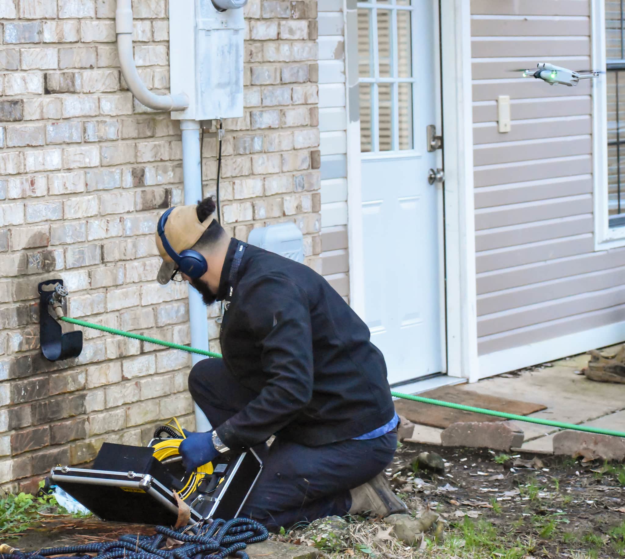 Technician working on piping beside a brick home